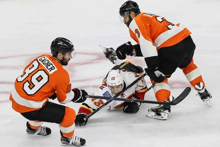 Flyers' Sam Gagner (89) and Radko Gudas surround  Flames' Johnny Gaudreau during the first period at the Wells Fargo Center in Philadelphia, Monday, February 29, 2016.