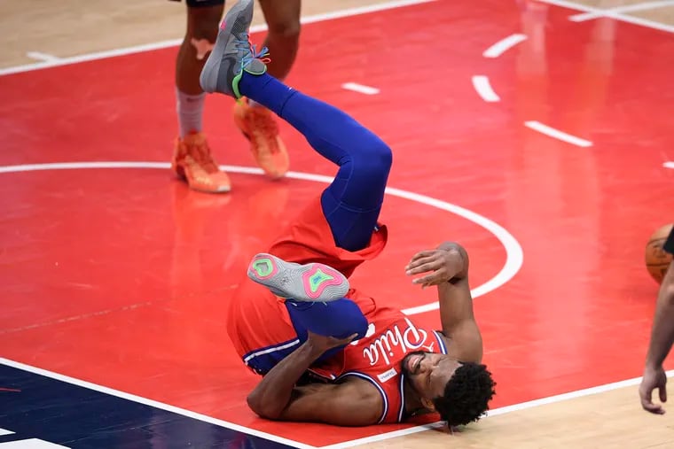 Philadelphia 76ers center Joel Embiid (21) grabs his knee after he was injured during the second half of an NBA basketball game against the Washington Wizards, Friday, March 12, 2021, in Washington. (AP Photo/Nick Wass).