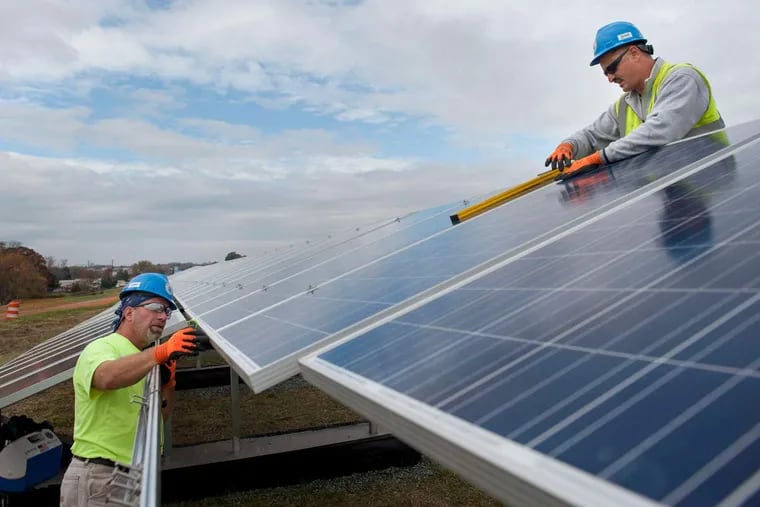 Al Pellegrini (left), of Vineland, and Bob Giandomenico, of Winslow, electricians with Riggs Distler, install solar panels for the PSE&G farm at the L&D Landfill in Lumberton, N.J.