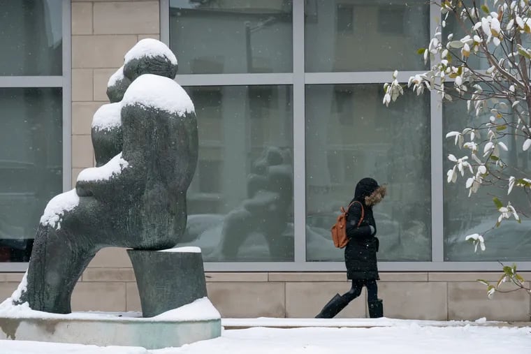 A pedestrian is bundled up against the snow while walking in front of the South Philadelphia Library on Monday morning.