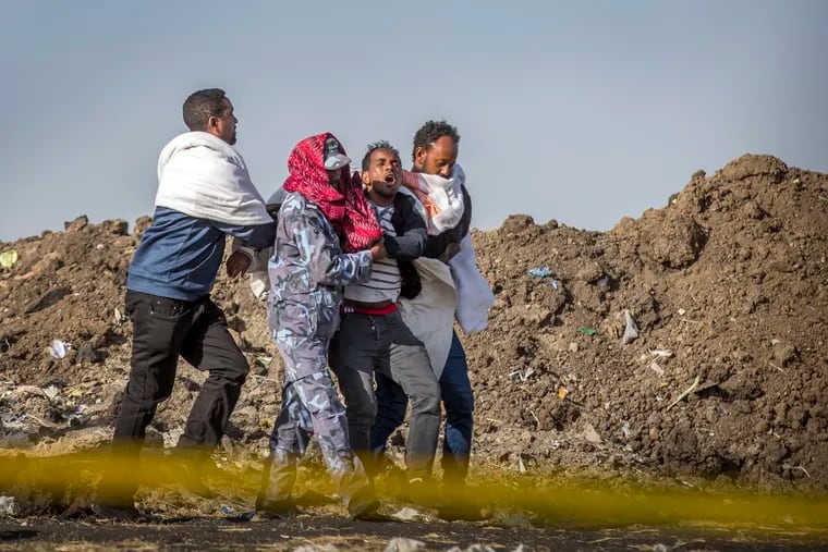 A grieving relative who lost his wife in the crash is helped by a member of security forces and others at the scene where the Ethiopian Airlines Boeing 737 Max 8 crashed shortly after takeoff on Sunday killing all 157 on board, near Bishoftu, or Debre Zeit, south of Addis Ababa, in Ethiopia Wednesday, March 13, 2019.