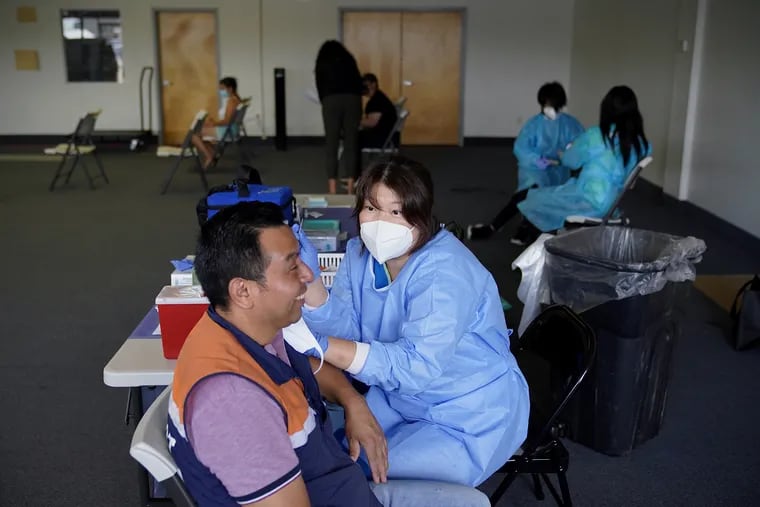 Nurse Hyun Lee (right) administers a COVID-19 vaccine to H Mart worker Pedro Pablo Garcia during a pop-up vaccination clinic at the H Mart shopping plaza in Philadelphia's Olney section on Saturday, June 26, 2021. The clinic was organized by Philly Counts, the city's Office of Immigrant Affairs, and Jaisohn Medical Center to increase vaccine access for underserved and immigrant communities.