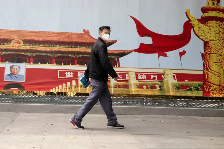 A resident wearing a mask against coronavirus walks past a government propaganda poster featuring Tiananmen Gate in Wuhan in central China's Hubei province. One theory holds that a virus from a natural source could have leaked accidentally from one of Wuhan's laboratories.