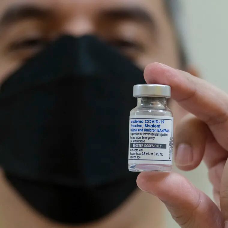 A pharmacist holds up a vial of the Moderna COVID-19 vaccine.