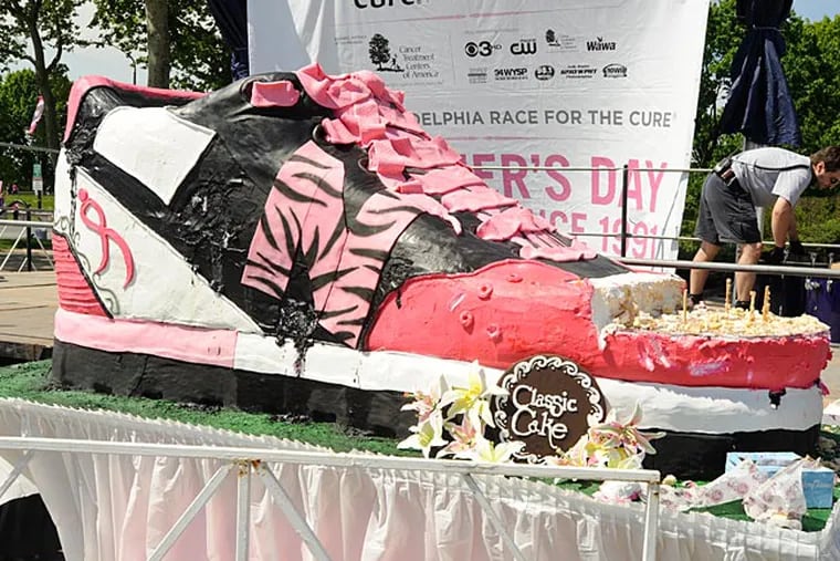 The partially eaten giant cake in the shape of a sneaker is free for the taking to breast cancer survivors near the main stage of the Susan G. Komen Race for the Cure. (Ron Tarver/ Staff Photographer)