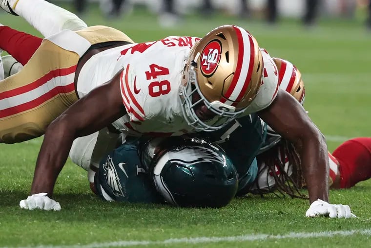 San Francisco 49ers linebacker Oren Burks falls on Eagles quarterback Jalen Hurts in the third quarter on Sunday, December 3, 2023 in Philadelphia.