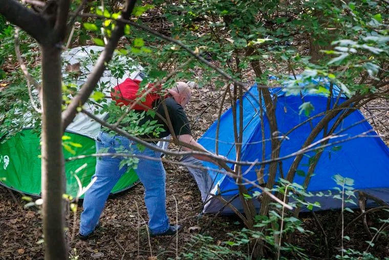 Richard Filson with Access Services inspects two tents along the bank of the Schuylkill River on Friday morning. Peco is clearing the area, which people living homelessly had used as an encampment.
