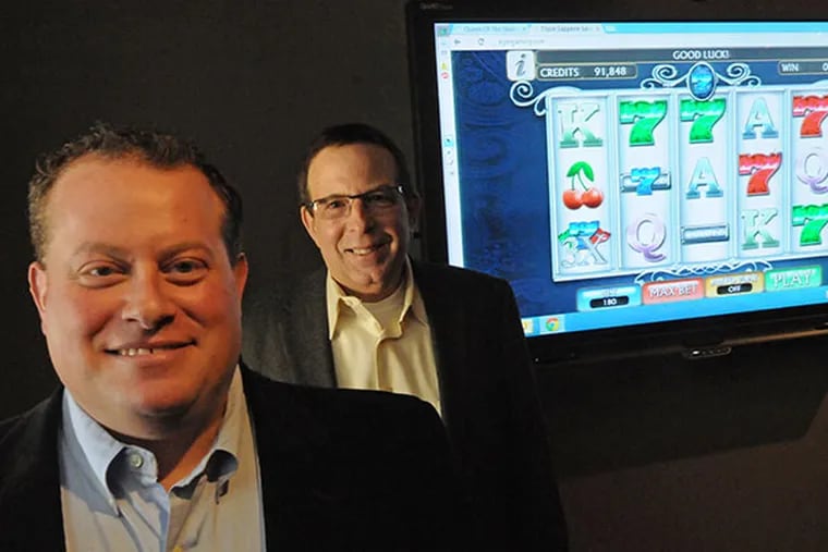 President Jason Peters, left, and CEO Howard Weiss, in front of one of KGM's games on a screen at KGM Gaming in Philadelphia on Feb. 11, 2014. ( APRIL SAUL  / Staff )