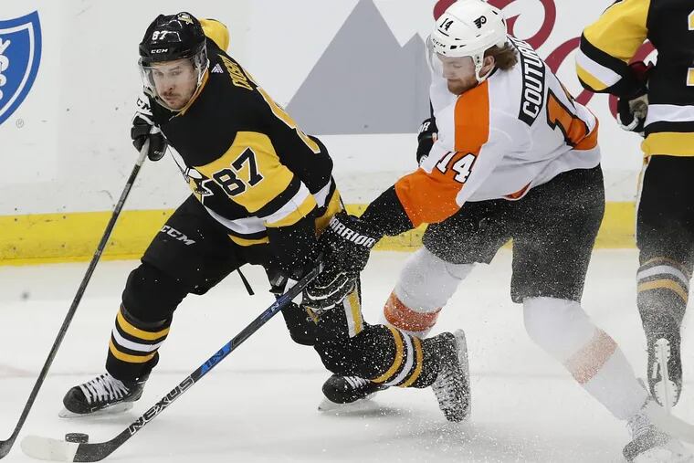 Pittsburgh’s Sidney Crosby (87) works the puck around Sean Couturier (14) during the third period of the Penguins’ 5-4 overtime win Sunday over the Flyers.