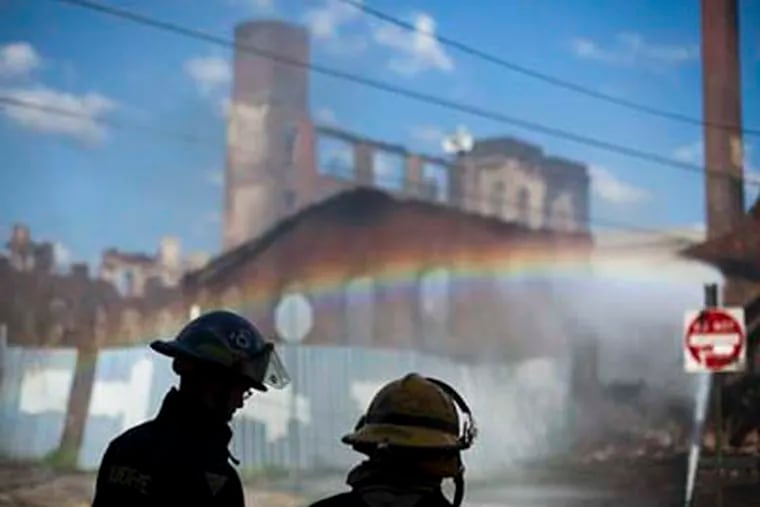 Firefighters view the aftermath of a fire in a warehouse on York Street near Kensington Avenue in Philadelphia on Monday, April 9, 2012. Two firefighters died after a wall collapsed on them while they fought the massive early-morning blaze. (AP Photo/Matt Rourke)