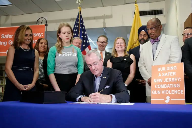 New Jersey Gov. Phil Murphy, center, signs a gun control bill during a ceremony in Berkeley Heights, N.J., Tuesday, July 16, 2019. Murphy has signed a measure aimed at making so-called smart guns available in the state. He also signed three other measures aimed at reining in gun violence.