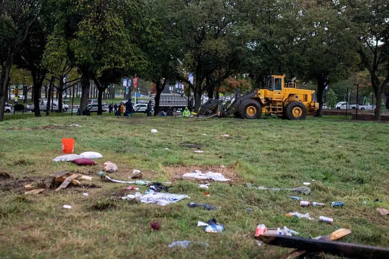 A front-end loader takes down the wooden pallet barricades at the Benjamin Franklin Parkway homless encampment on Friday. Many residents thought they were being invaded.