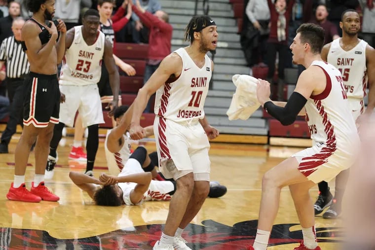 Troy Holston, center, and Taylor Funk, right, of St. Joseph's celebrate after their 61-60 victory over Davidson.