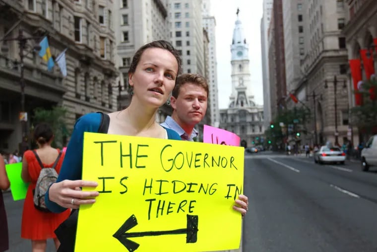 Laura Smith, left, and Jordan Konell, both summer interns at Public Interest Law Center of Philadelphia, hold signs to rally pedestrians and passers-by to react about funding Philadelphia schools. Will schools open on Sept. 8 as scheduled? It's still very much an open question.