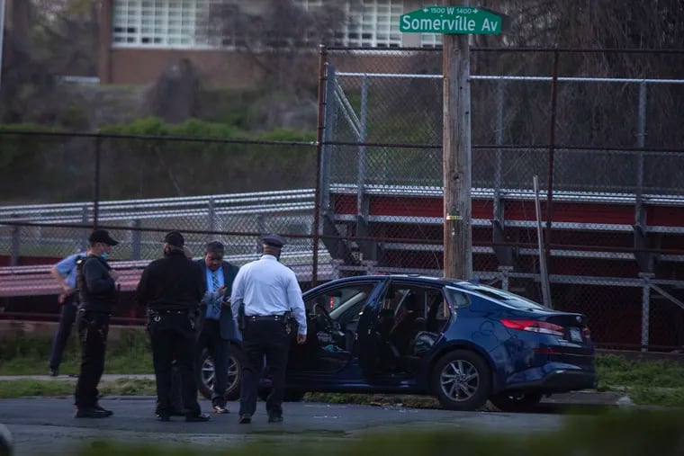 Philadelphia officers stand in front of a vehicle involved in the officer shooting at 15th Street and West Somerville Avenue in North Philadelphia on Wednesday.