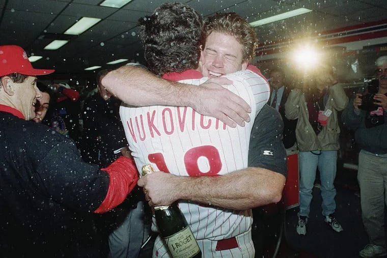 Philadelphia Phillies catcher Darren Daulton hugs Coach John Vukovich in post game celebration in the Phillies locker room after defeating the Atlanta Braves in Game 6 of the National League Playoff at Veterans Stadium, Oct. 13, 1993.