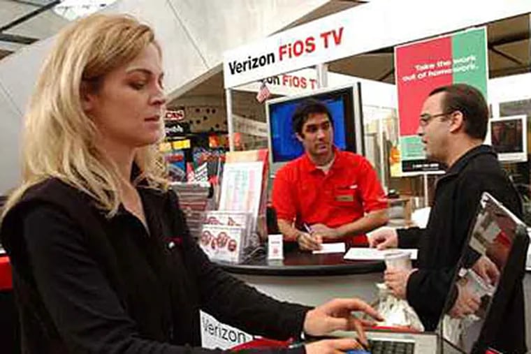In this file photo,  manager Jamie Camp reviews data at a Columbia, MD., store. Verizon announced today that it wants to offer FiOS TV service in Philadelphia. (Jonathan Wilson / Inquirer)