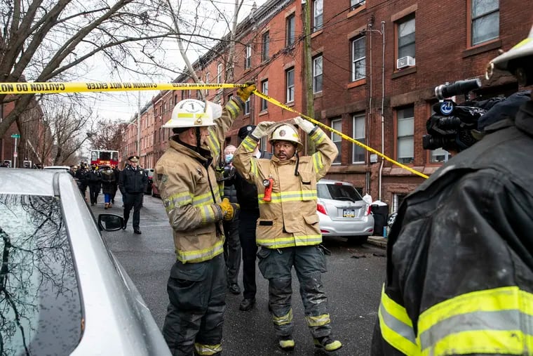 Firefighters walk towards a press conference at the scene of a fatal house fire on the 800 block of 23rd Street in the Fairmount section of Philadelphia on Wednesday.