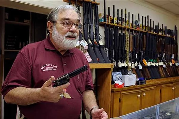 In this photo taken Wednesday, Dec. 19, 2012, gun store owner Dave Burdett talks about gun rights as he displays a hand gun in his store in College Station, Texas. Burdett, who owns an outdoors and adventure shop across the street from the sprawling Texas A&M University campus in College Station, says his affinity for guns is rooted in history, not sport. (AP Photo/Pat Sullivan)