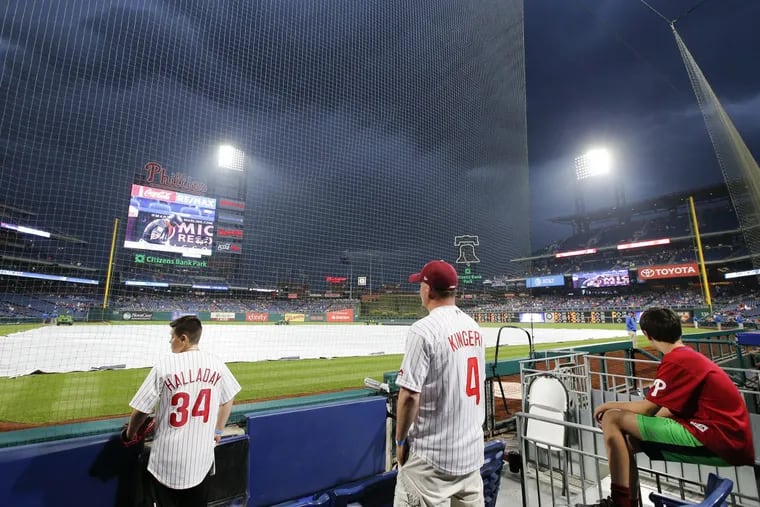 Fans watch dark clouds roll over Citizens Bank Park during a delay before the Phillies play the New York Mets on Saturday, May 12, 2018 in Philadelphia.