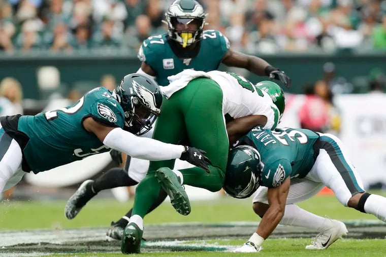 Eagles ilinebacker Zach Brown (left) and defensive back Craig James stop New York Jets running back Le'Veon Bell in the first quarter.