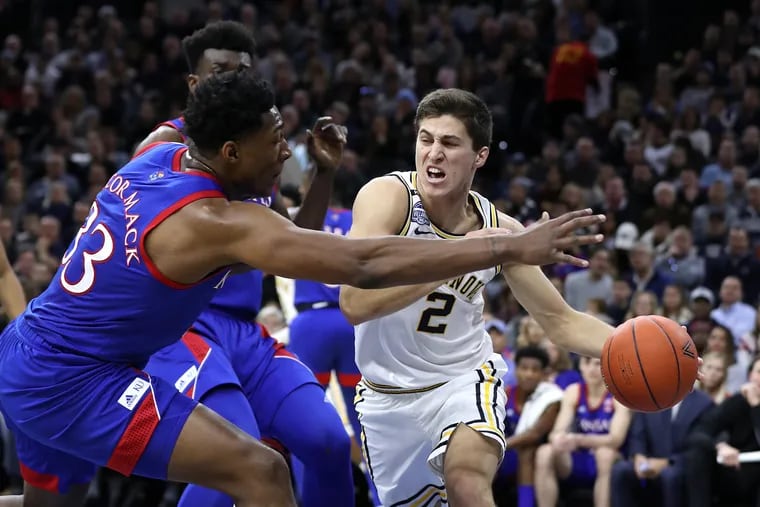 Collin Gillespie, right, passes to a teammate around the  grasp of David McCormack of Kansas during the 1st half at the Wells Fargo Center on Dec. 21, 2019.