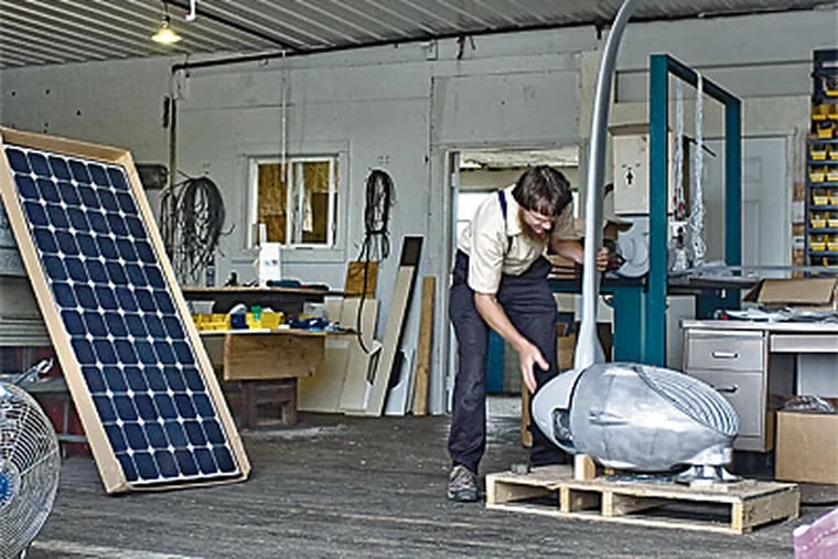 Elam Beiler works on a wind turbine in the shop of his Advanced Solar Industries firm in Ronks, Lancaster County. Beiler has been selling solar products for 15 years. (Clem Murray / Inquirer)
