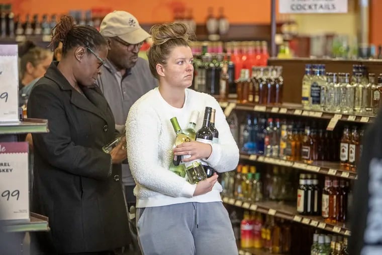 Customers waiting in line on March 17 before the closing time at the Fine Wine and Good Spirits store in Ivy Ridge Shopping Center in Roxborough.