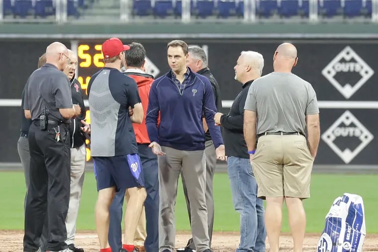 Phillies Vice President and General Manager Matt Klentak (center) talks to players and officials discuss field conditions before the Phillies and the Washington Nationals play on Monday, September 10, 2018. The game was called off and the two teams will play a double header tomorrow.