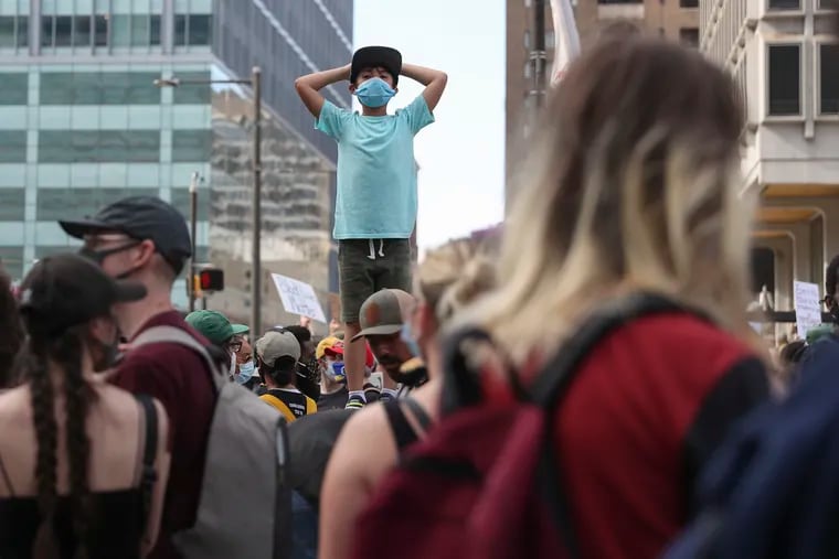 A young boy stands above the crowd on Market street in Philadelphia as people protest on Saturday, June 6, 2020, against the Minneapolis police custody death of George Floyd.
