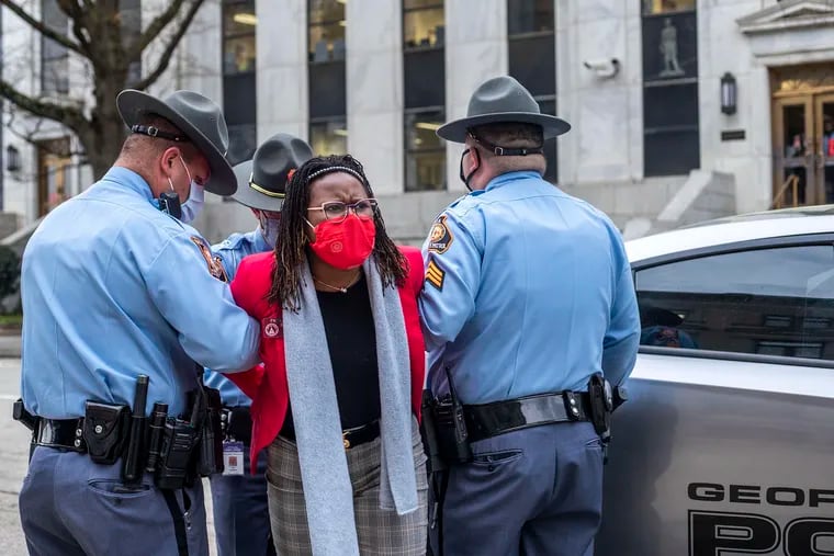 State Rep. Park Cannon, D-Atlanta, is placed into the back of a Georgia State Capitol patrol car after being arrested by Georgia State Troopers at the Georgia State Capitol Building in Atlanta, Thursday, March 25, 2021. Cannon was arrested by Capitol police after she attempted to knock on the door of the Gov. Brian Kemp office during his remarks after he signed into law a sweeping Republican-sponsored overhaul of state elections that includes new restrictions on voting by mail and greater legislative control over how elections are run.