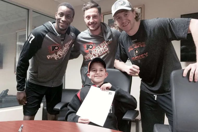 Tony Campisi, 11, shows off the one-day contract he signed with the Flyers. Behind him are (from left) Wayne Simmonds, Mark Streit, and Jake Voracek.