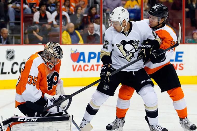 Steve Mason, left, holds on to the puck as Pittsburgh Penguins' Chuck Kobasew, center, and Flyers' Claude Giroux, right, watch in the first period of an NHL hockey game, Thursday, Oct. 17, 2013, in Philadelphia. (Tom Mihalek/AP)
