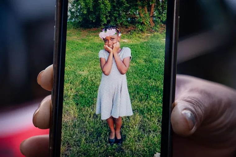 A relative holds up a cellphone with a photo of Fanta Bility.