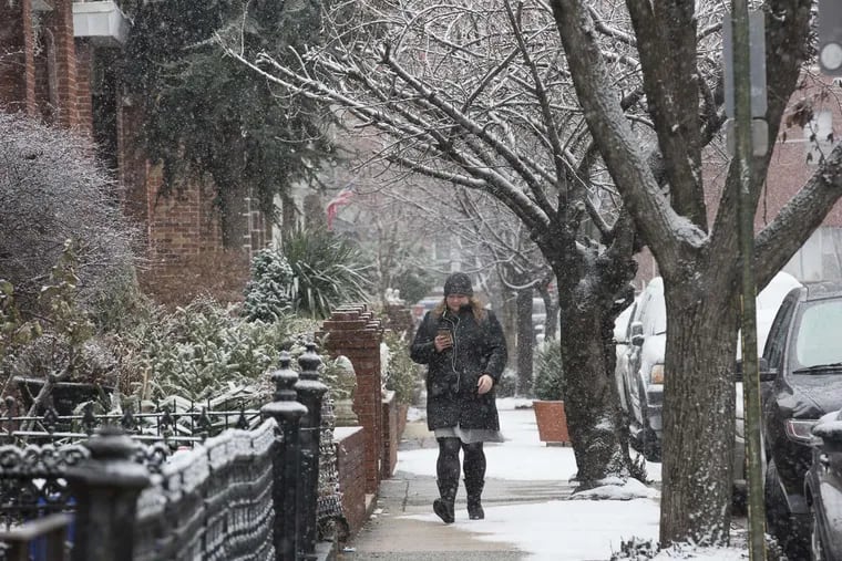 A light snow falls in South Philadelphia, as a pedestrian makes her way down the street, Wednesday, Jan. 17, 2018. JESSICA GRIFFIN / Staff Photographer