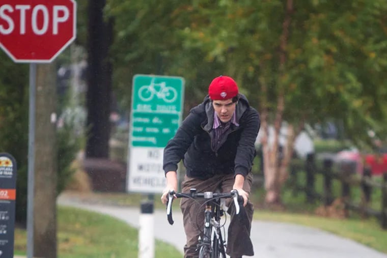 Montgomery County planners are getting ready to solicit the public's input on a countywide master plan through 2040. Refurbishing Montco's  trails are among the items the officials hope to look at. Here, Kevin Readinger, 20 of Conshohocken peddles his bike through the rain on the Schuylkill River trail near its railhead in Conshohocken on Thursday. (Ed Hille/Staff Photographer)