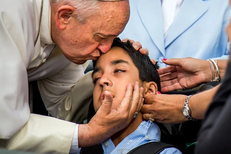 In this photo provided by World Meeting of Families, Pope Francis kisses and blesses Michael Keating, 10, of Elverson, Pa after arriving in Philadelphia and exiting his car when he saw the boy, Saturday, Sept. 26, 2015, at Philadelphia International Airport. Keating has cerebral palsy and is the son of Chuck Keating, director of the Bishop Shanahan High School band that performed at Pope Francis' airport arrival. (Joseph Gidjunis/World Meeting of Families via AP) MANDATORY CREDIT