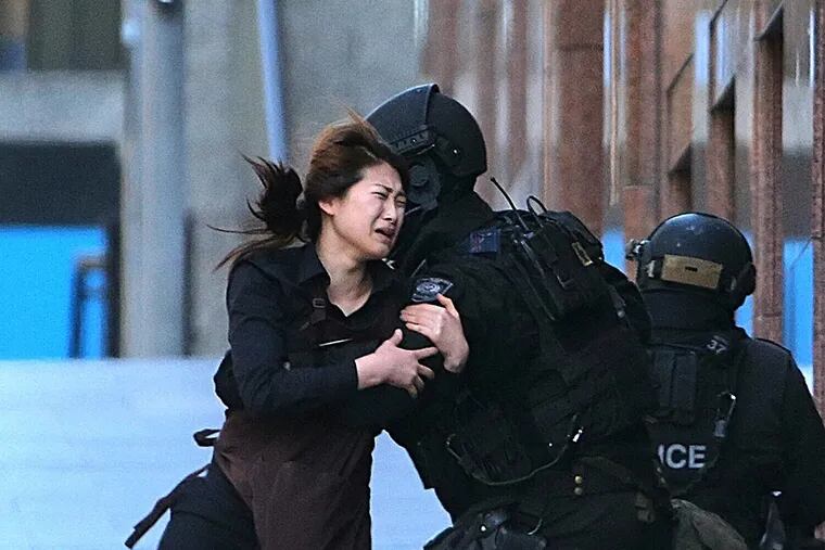 A hostage runs into the arms of a police officer after escaping from a cafe in the central business district of Sydney, Australia. The gunman, a self-styled Islamic cleric, was later killed. ROB GRIFFITH / AP
