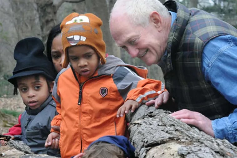 Howard Brosius, who teaches young children to grow and enjoy vegetables, searches for foxes in a hollow log at Awbury Arboretum with Ishmea'il Mathis (left), 3, and Yaquin Johnson, 4. APRIL SAUL / Staff Photographer