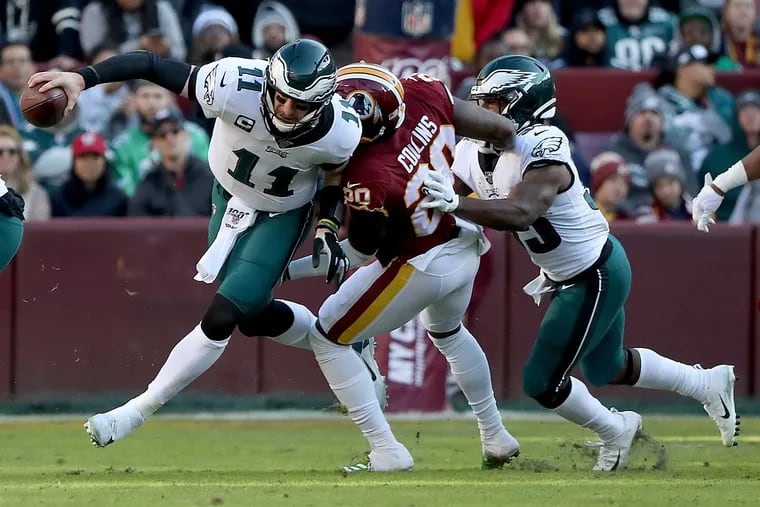 Eagles quarterback Carson Wentz scrambles away from Washington’s Landon Collins,  Wentz threw an incomplete pass on the play.