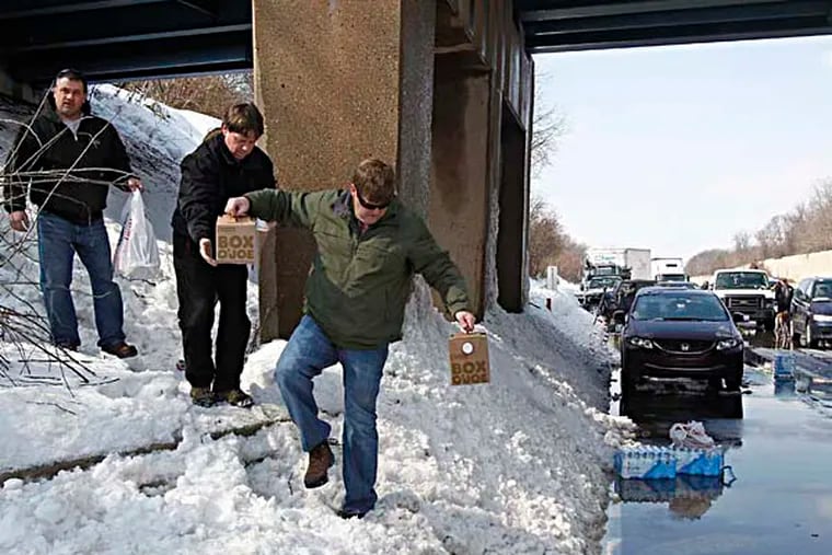 Michael Kucera from South Hampton, left, brings donuts and coffee to stranded motorists on the Pennsylvania Turnpike on Friday, February, 14, 2014. Michael Porter, center, and Jerry Cousar, right, help him bring the refreshments down to the road.( AKIRA SUWA  /  Staff Photographer )