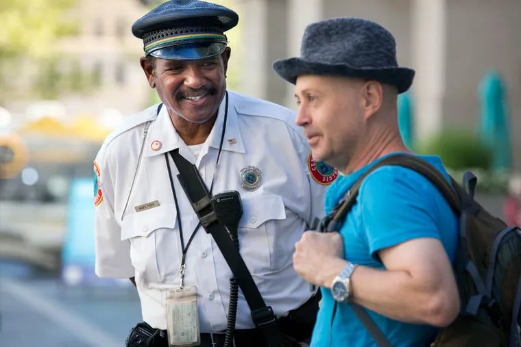 Center City District Service Representative Moses Pierce (left) gives directions to Drian Von Golden, a visitor from Australia, in Dilworth Plaza.
