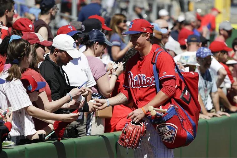 Phillies minor-league outfielder Mickey Moniak signs his autograph for fans before the Phillies played a split-squad  game against the Baltimore Orioles at Spectrum Field.