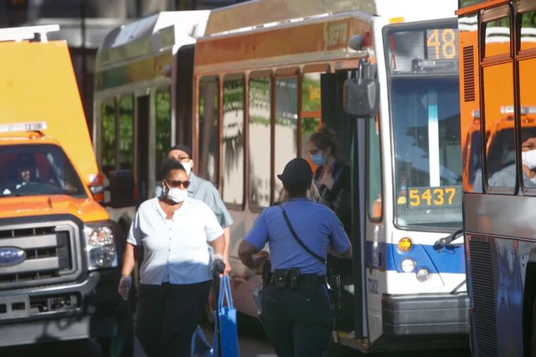 A SEPTA transit officer checks in with bus drivers at 15th and Market Streets Monday morning. Monday is the first day SEPTA is requiring masks for riders.