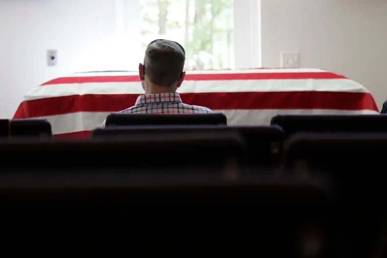 In this April 3, 2020, photo, Eric Coleman sits in front of his father's casket during his funeral, in Lexington, S.C. J. Robert Coleman's widow and three sons were spaced apart to follow social distancing guidelines during the coronavirus outbreak. (AP Photo/Sarah Blake Morgan)