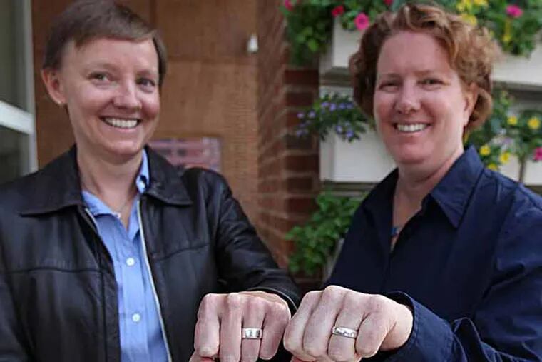 Isabelle Barker, left, and Cara Palladino, right, show off their wedding rings they exchanged when they were legally married in the State of Massachusetts.  Two Pennsylvania women have filed a federal lawsuit seeking national recognition of same-sex marriage. Though married in Massachusetts, Cara Palladino and Isabelle Barker say their status is not recognized in Pennsylvania, where they now live with a four-year-old son. Marriages of same-sex couples in 13 states and the District of Columbia are not recognized in the other 37 states. The suit seeks to change this.	 09/26/ 2013 ( MICHAEL BRYANT / Staff Photographer  )