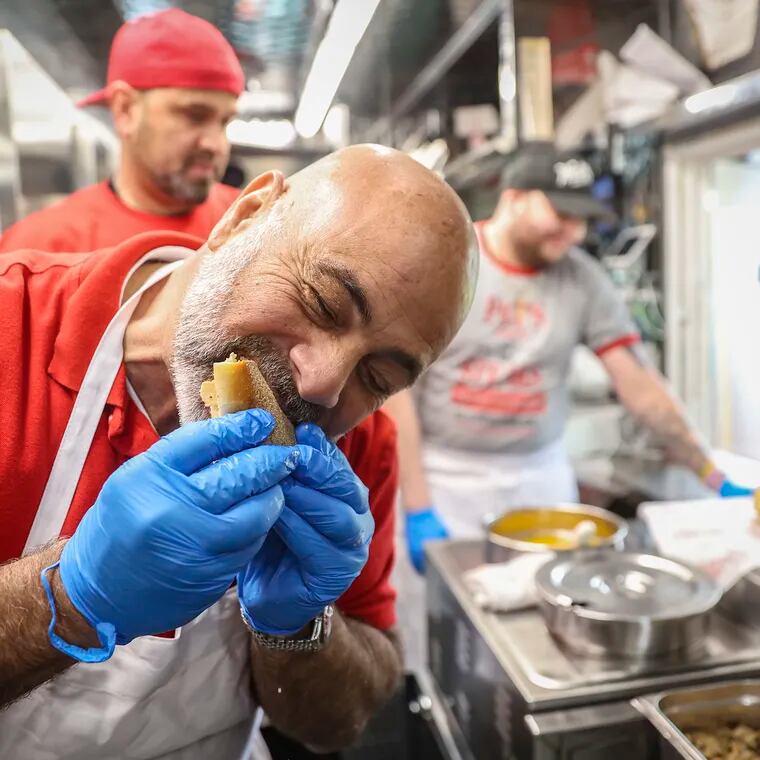 Frank Olivieri Jr., owner of Pat's King of Steaks, sampling a chicken cheesesteak inside the truck parked outside of the shop at Ninth Street and Passyunk Avenue.