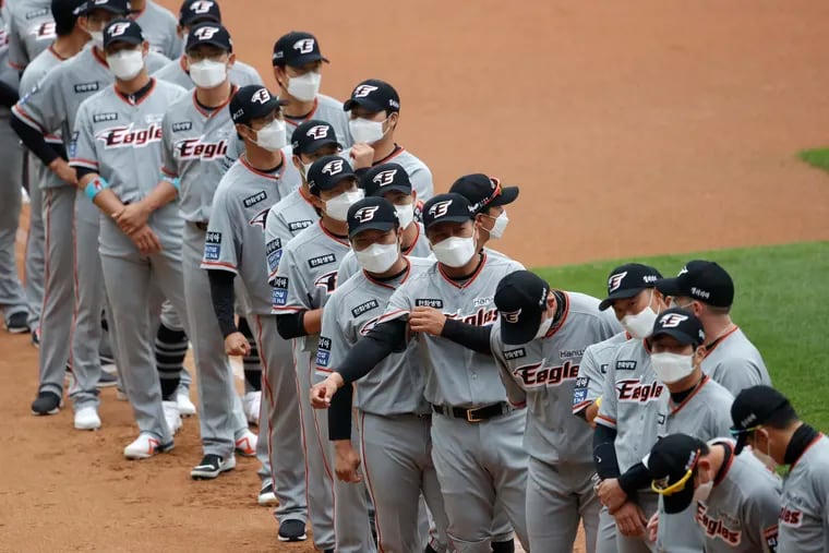 Hanwha Eagles players wearing face masks line up during the start of their regular season baseball game Tuesday against SK Wyverns in Incheon, South Korea.