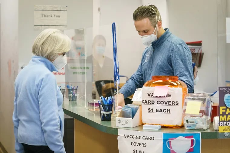 Charlotte Schwartz, left, is checked in by Marc Ost, right, co-owner of Eric's RX Shoppe, to receive her 4th covid vaccine, at Eric's RX Shoppe Vaccine Clinic, in Horsham, PA, Wednesday, February 2, 2022.