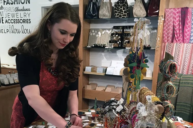 Manager Mieke Ellis straightens out jewelry on a display table at the new Lou Lou store in Center City. The store is the company's 25th in the U.S.